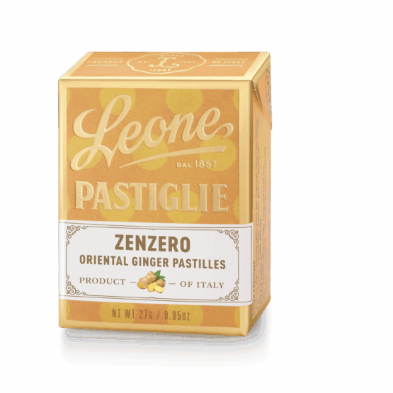 A small, clear tin filled with round, ginger-flavored pastilles. The tin has a brown and white label with the Pastiglie Leone logo and the flavor name in Italian.