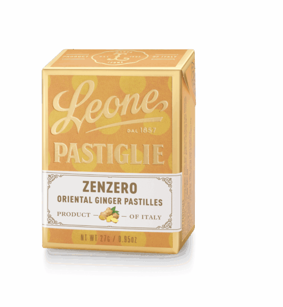 A small, clear tin filled with round, ginger-flavored pastilles. The tin has a brown and white label with the Pastiglie Leone logo and the flavor name in Italian.